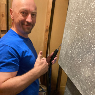 Energy Auditor taking a reading of a home appliance. He's smiling and giving a thumbs up.